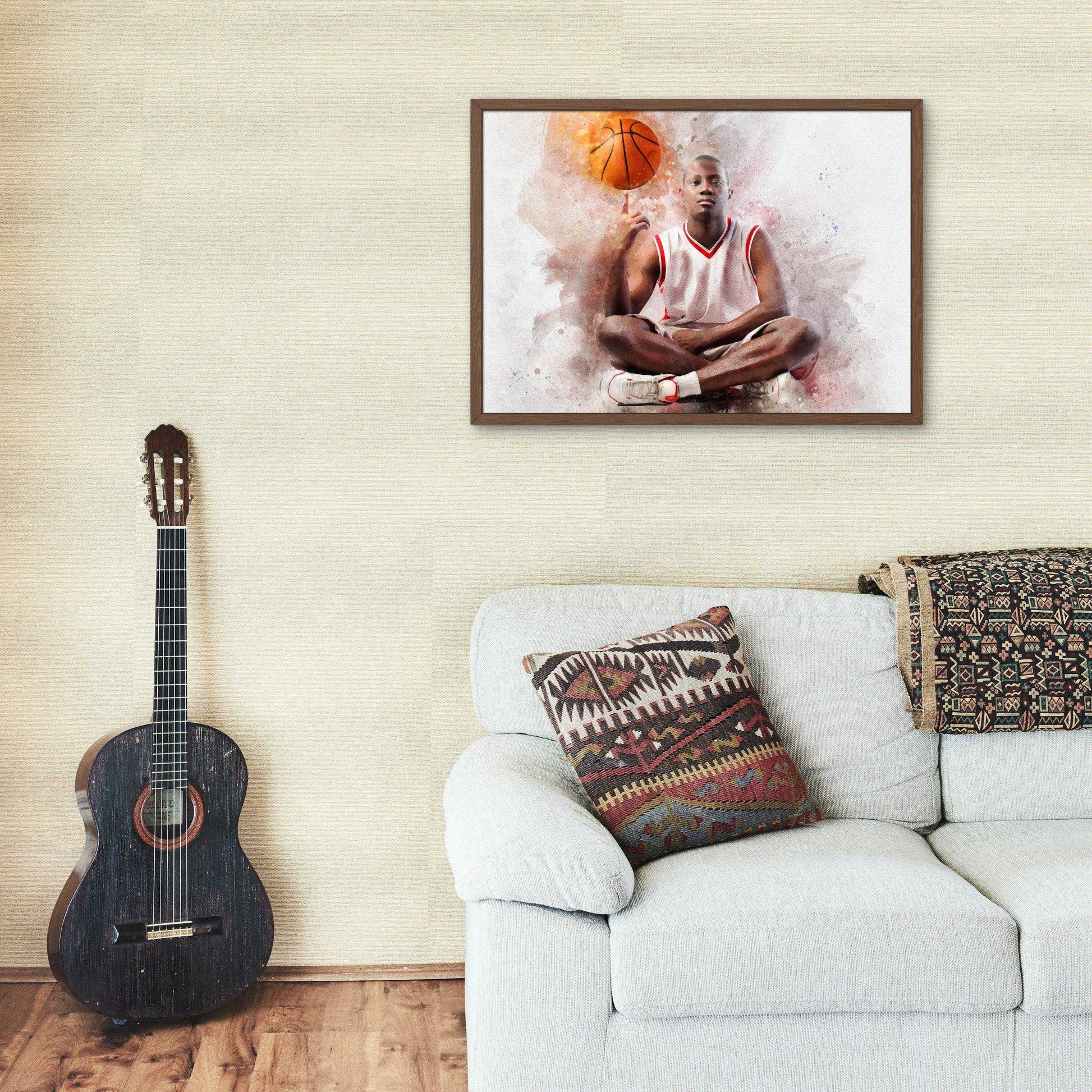 A framed watercolor-style portrait of a male basketball player seated cross-legged, balancing a basketball on his finger, hangs on a lightly textured wall. This artistic rendering is a great example of Custom Basketball Gifts. Below the portrait, a light-colored sofa with a patterned throw pillow and blanket sits beside a dark acoustic guitar, creating a cozy living space.