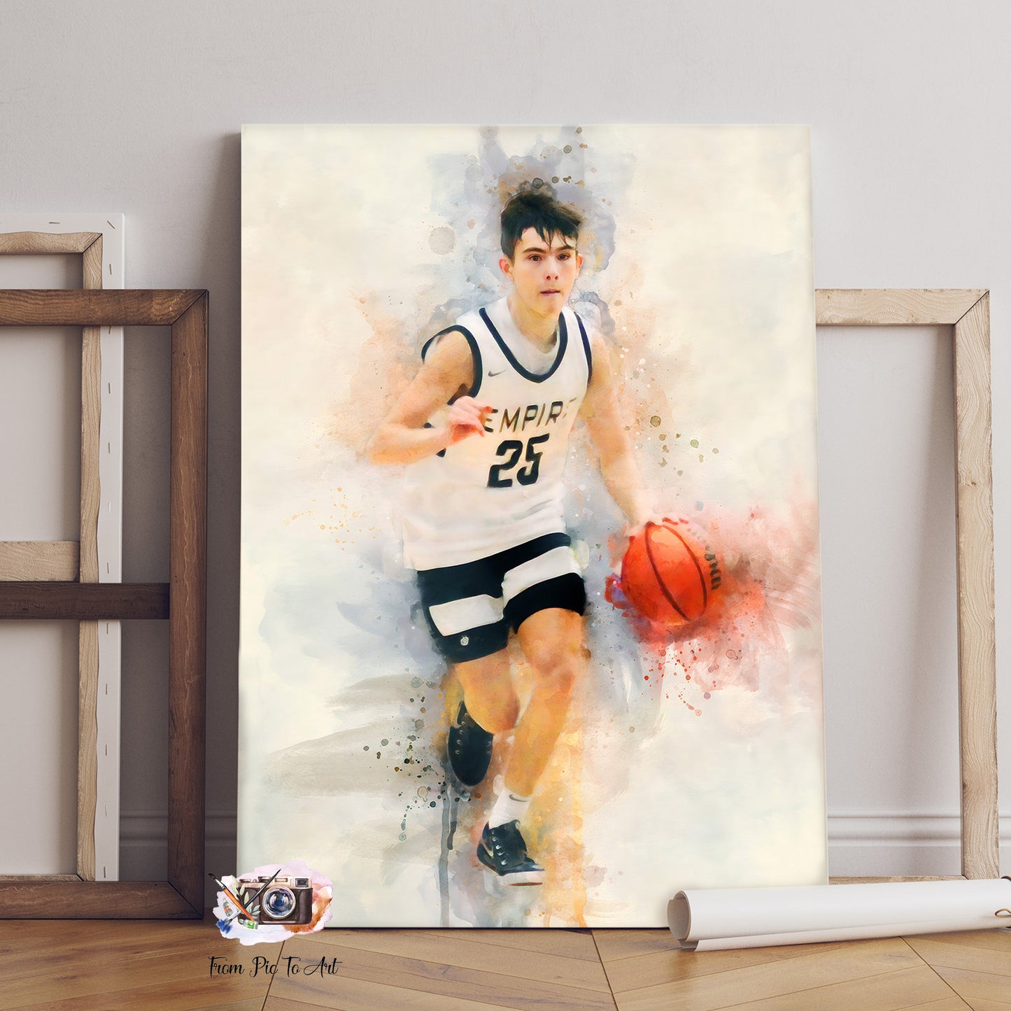 A dynamic watercolor-style portrait of a young male basketball player in a white and black "EMPIR 25" jersey, dribbling an orange basketball. The artwork is presented as a Custom Basketball Gift, with a subtle "From Pic To Art" logo in the bottom left corner, surrounded by two empty wooden frames and a rolled-up poster.